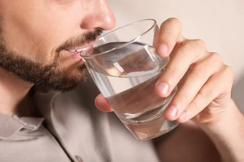 Man drinking water on blurred background, closeup. Refreshing drink Stock Photos