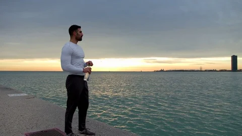 Man is drinking water on the ebankment in the front of the sea. Downtown with Video stock 82642321