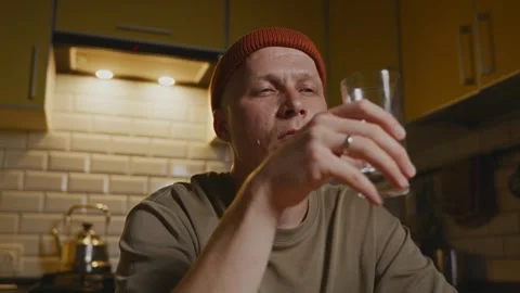 Man drinking water in minimalist kitchen showing daily comfort 库存影片 320496656