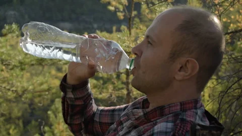 Man drinking water in nature. Sits on a folding chair in a wellness camp. Stock Footage 95090193