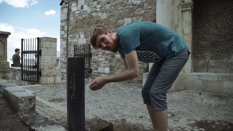 Man drinking water. Portrait of a young man drinks from a water fountain in the Stock Footage 79317872