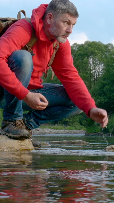 Man drinking water from river while hiking outdoors in natural environment Stock Footage 335439565