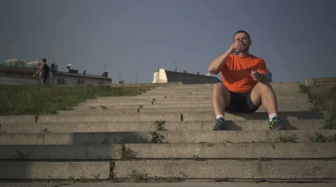 Man is drinking water, sitting on staris. 動画素材 52695457
