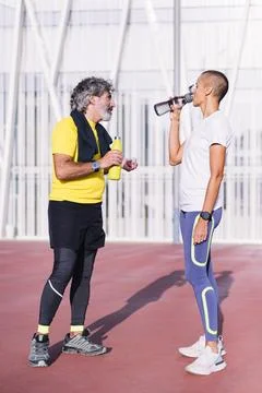 Man drinking water with trainer before training Stock Photos