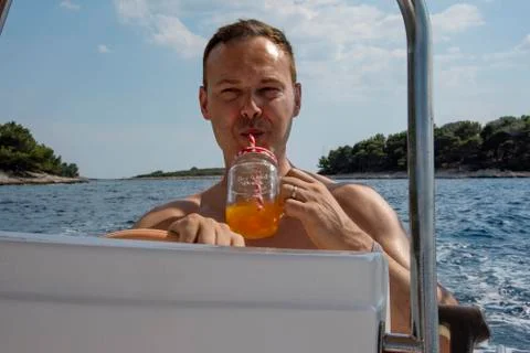 Man drinking while driving a speed boat during vacation Stock Photos
