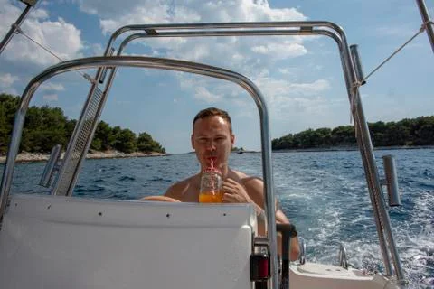 Man drinking while driving a speed boat during vacation Stock Photos