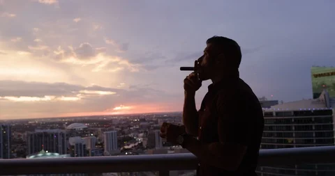 Man drinking whisky while smoking cigar in balcony Stock Footage 116349895