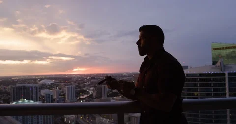 Man drinking whisky while smoking cigar at dusk Stock Footage 116350282