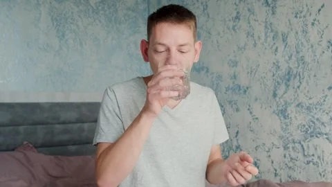 Man drinking white capsule with collagen with glass of water while sitting on Stock Footage 249650988