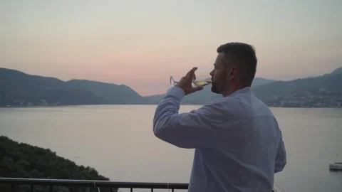 Man drinking white wine standing on the patio of the luxury hotel Stock Footage 280006327