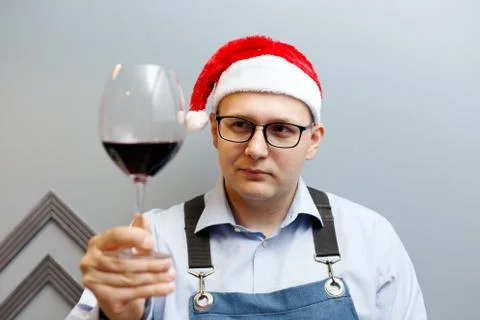 A man is drinking wine in a santa hat Stock Photos