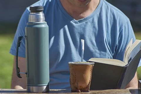 Man drinking Yerba Mate while reading a book. Stock Photos