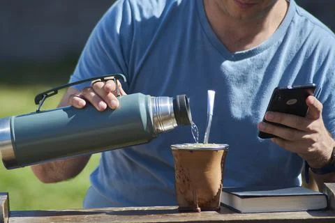 Man drinking Yerba mate while looking at his cell phone Stock Photos