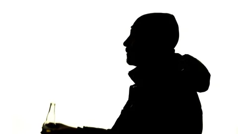 Man drinks alcohol from a bottle and smokes a cigarette. Side view. Silhouette Video stock 101772719