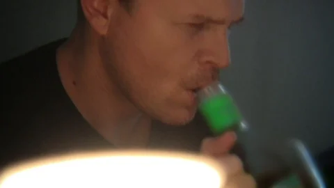 A man drinks from an alcoholic bottle and takes pills. Video stock 99612494