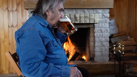 Man drinks beer before fireplace. Stay at home. Coronavirus Covid-19. Stock Footage 128457675