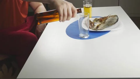 A man drinks beer with fish.At home at the dinner table. Stock Footage 130942012