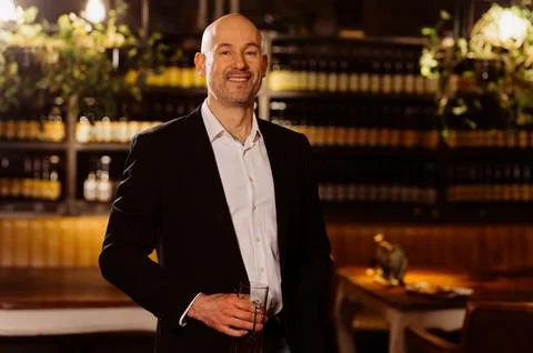 A man drinks beer. Side view of handsome bald man drinking beer in evening pu Stock Photos