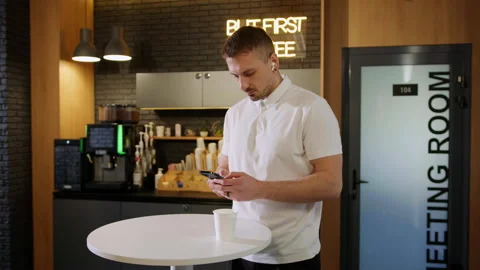 A man drinks coffee and surfs the phone in an office cafe Stock Footage 195204337