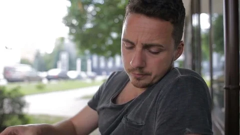 A man drinks coffee in a cafe and looks around Stock Footage
