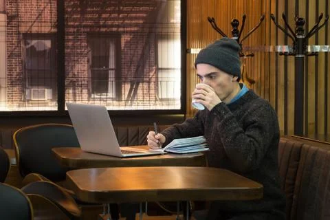 Man drinks coffee at cafe in the evening.  Young male in casual winter clothe Stock Photos