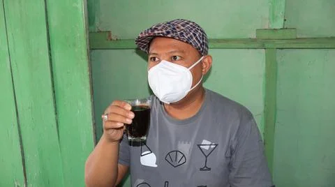 Man drinks coffee but still has to wear a mask Stock Photos