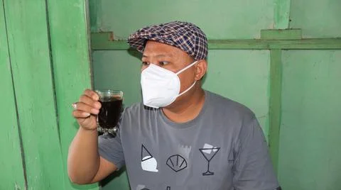 Man drinks coffee but still has to wear a mask Stock Photos