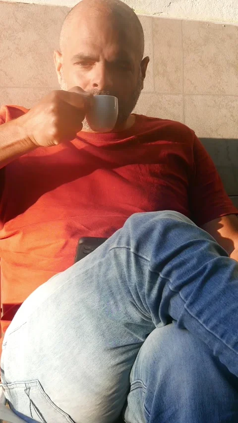 A man drinks coffee in the sun while checking his smartphone. Drinking coffee Stock Footage 319174282
