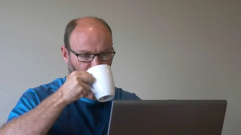 Man drinks coffee while working on laptop Stock Footage 88456487