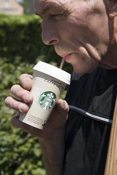 A man drinks cold latte coffee from a starbucks cardboard cup on a hot sunny day Stock Photos