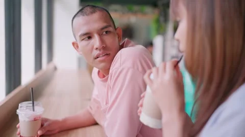 A man drinks a drink at a restaurant and looks at his lover using a smartphone t Stock Footage 265143268