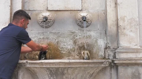 A man drinks from a drinking fountain, washes his face with fresh and cool water Stock Footage 209158432