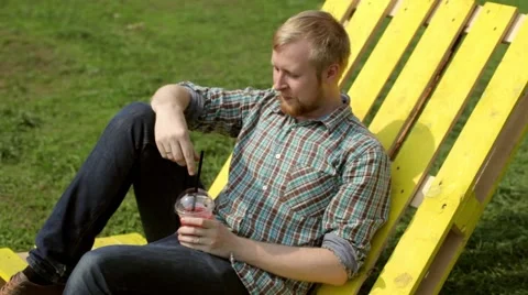 Man Drinks Fruit Juice Sitting on a Lounger 스톡 동영상 66373712