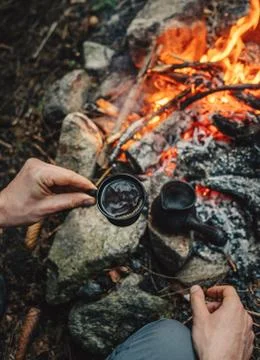 Man drinks hot coffee making on campfire Foto stock