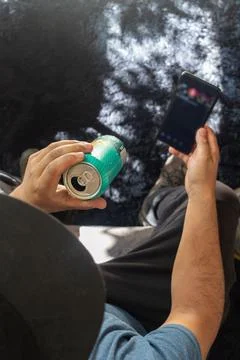 Man drinks a soda while checking his cell phone, aerial view Stock Photos
