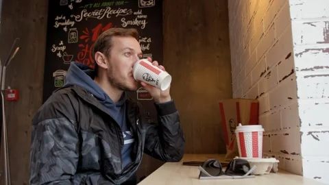Man drinks soft drink from a paper cup at a KFC. Minsk, Belarus - April 2, 2026 Stockbeeldmateriaal 333641287