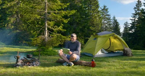 The man drinks tea and looks at the map in the Camping. Stock Footage 156969074