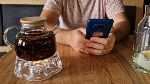 A man drinks tea and uses a mobile phone app for online business communication. Stock Footage 243168630