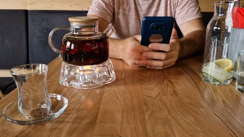 A man drinks tea and uses a mobile phone app for online business communication. Stock Footage 243257063
