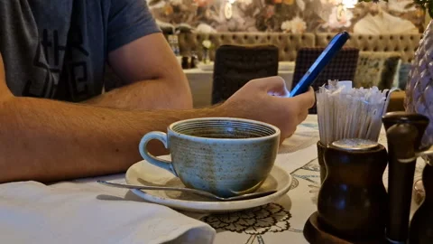 A man drinks tea and uses a mobile phone app for online business communication. Stock Footage 244315981