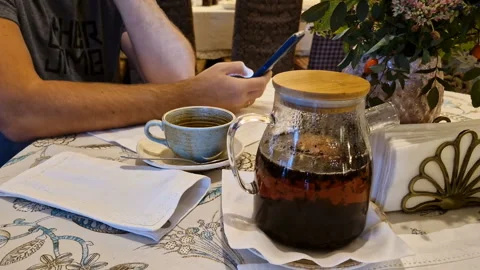 A man drinks tea and uses a mobile phone app for online business communication. Video stock 244391864