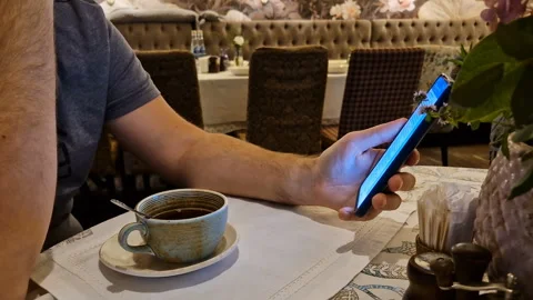 A man drinks tea and uses a mobile phone app for online business communication. Stock Footage 244773696