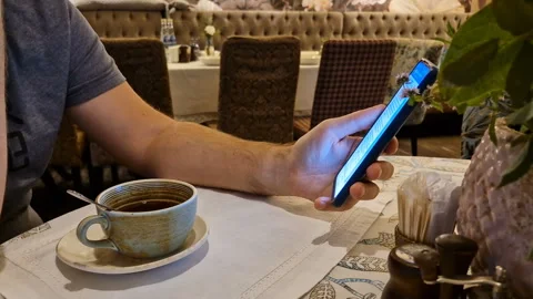 A man drinks tea and uses a mobile phone app for online business communication. Stock Footage 244774190