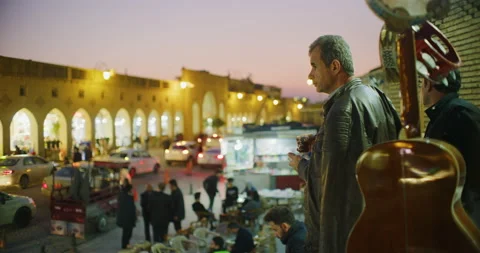 Man Drinks Tea During Sunset Time At Grand Bazaar And The Citadel in Erbil, Iraq Stock Footage 150127664