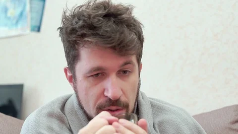 A man drinks tea with lemon. He has a cold, headache, fever, chills. 스톡 동영상 100326579