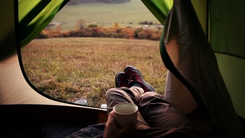A man drinks tea lying in a tent with one leg on another 動画素材 97614631