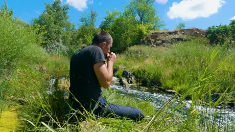A man drinks tea in nature by the river. Peace of mind and enjoyment of life Stock-Footage 199191880
