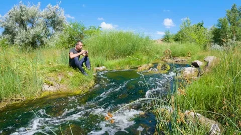 A man drinks tea in nature by the river. Peace of mind and enjoyment of life 스톡 동영상 199192037