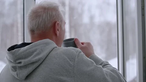 A man drinks tea at an open window in a snowfall Stock Footage 166992105