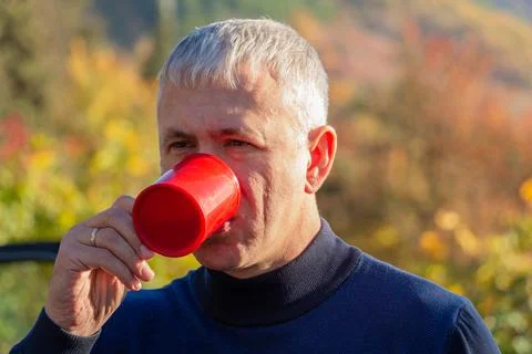 A man drinks tea or coffee in nature. Stock Photos